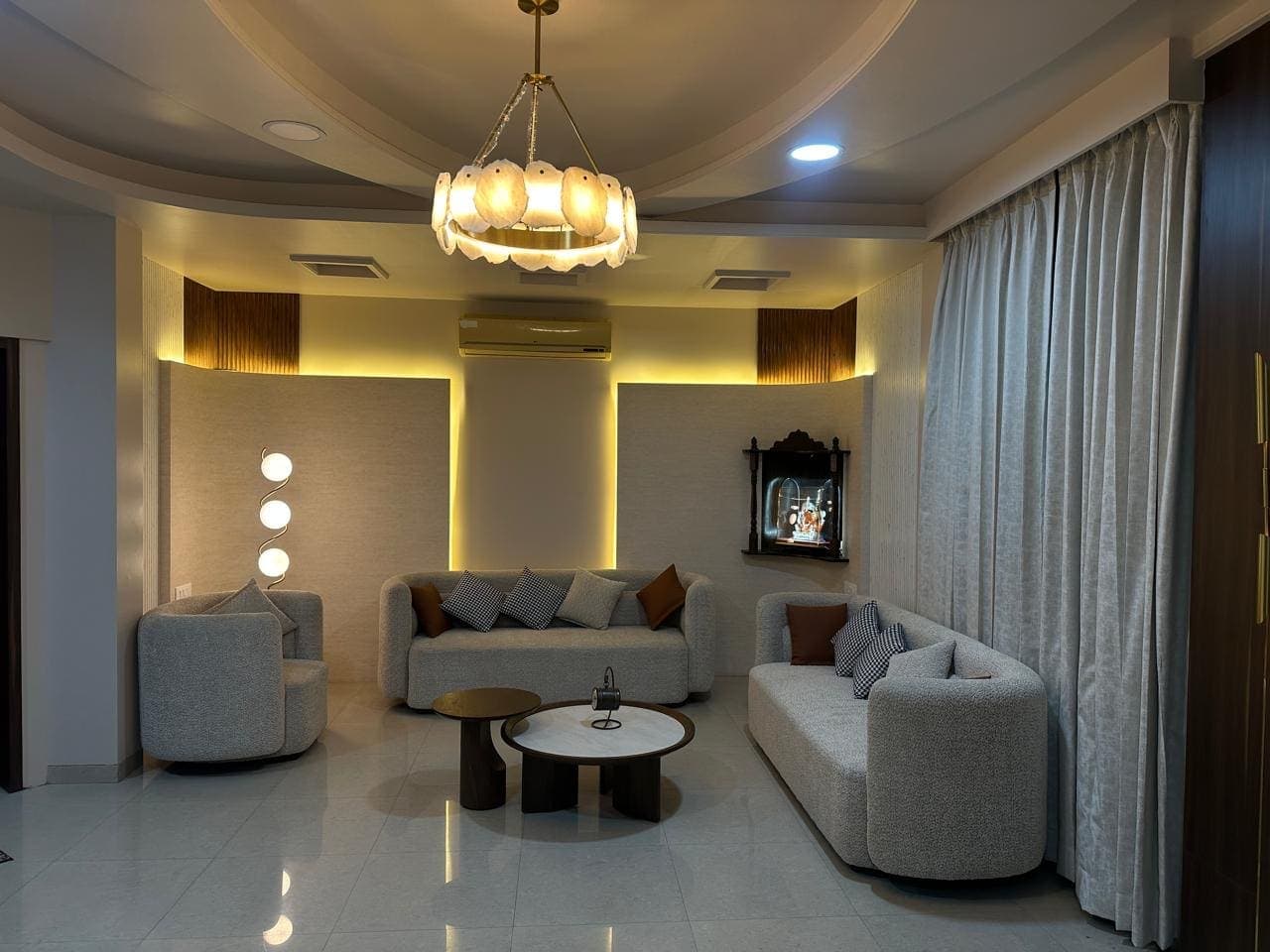 Living room under a stepped circular ceiling and a ring chandelier, with cove-lit wall panels and boucle seating